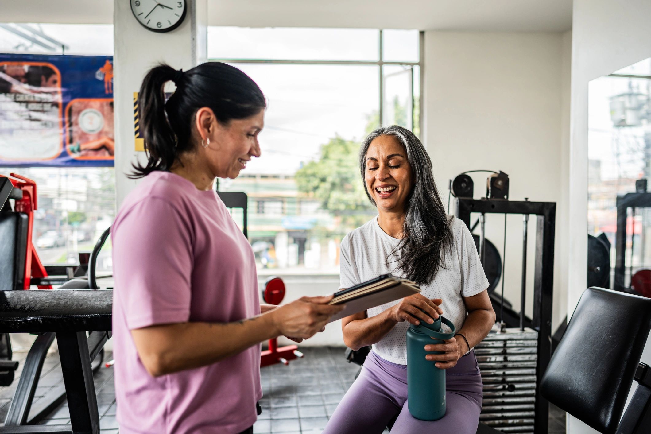 Fitness instructor consulting an athlete with a tablet in a gym